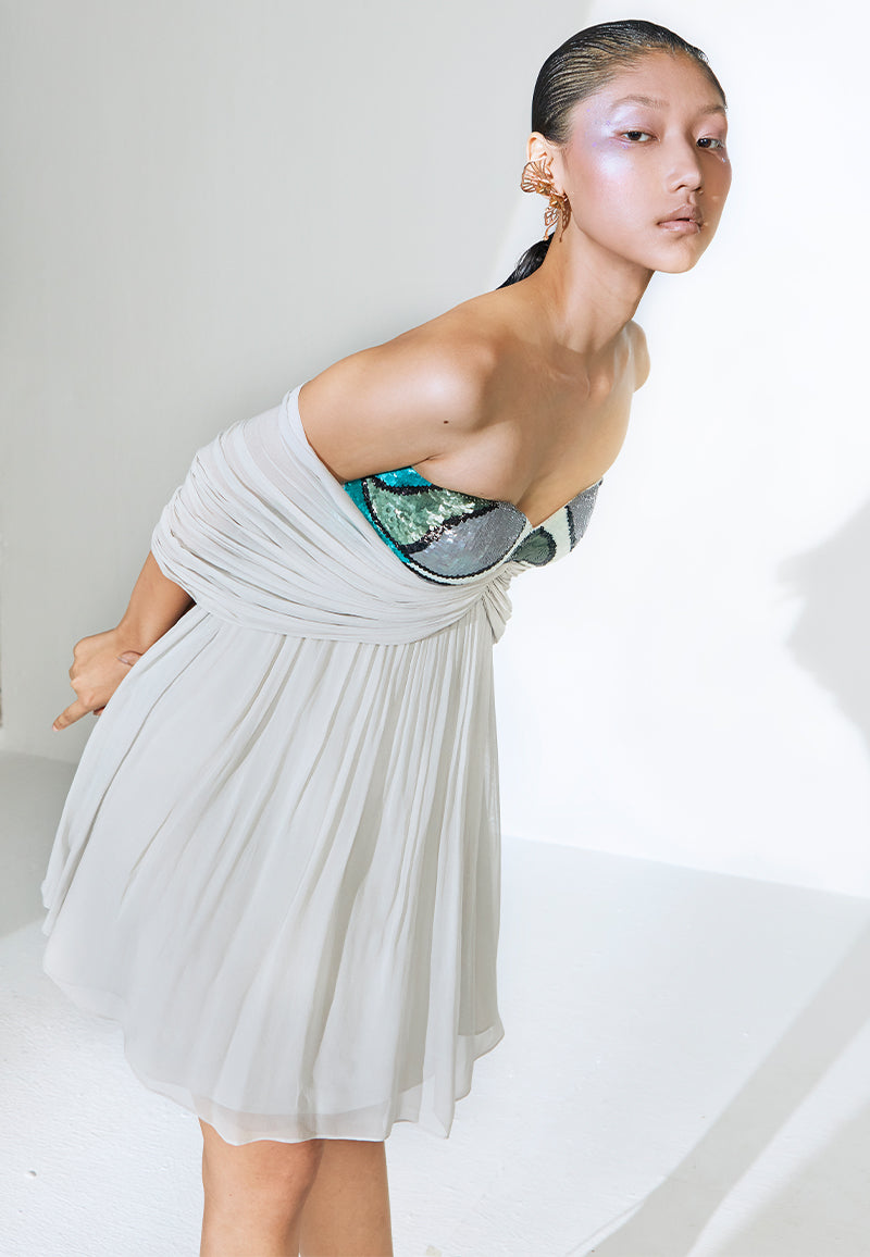 Hand-embroidered in olive green, off-white, blue and black sequins, this mini dress is constructed in lush gray georgette. The bandeau dress features a sweetheart neckline with loosely draped sleeves falling on the elbow, giving the dress a very airy and sophisticated look. The dress from the under bust is flared for comfort and ease. Pair this butterfly dress with a pair of pencil heels and diamonds for your next dinner or night out.