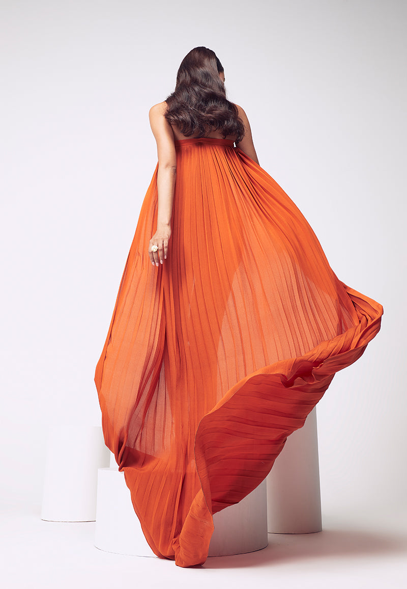 New style figure-hugging jumpsuit. Crafted in pure silk crepe in burnt orange with inseam pockets which are perfect for your next soiree or even a beach party. Easy to wear this ankle-length bodycon jumpsuit comes with a detachable pleated trail with a hook and eye closure for easy access and confort. Create multiple looks for multiple events with detachable, functional clothing. Complete the look with heeled sandals and minimal gold jewelry.