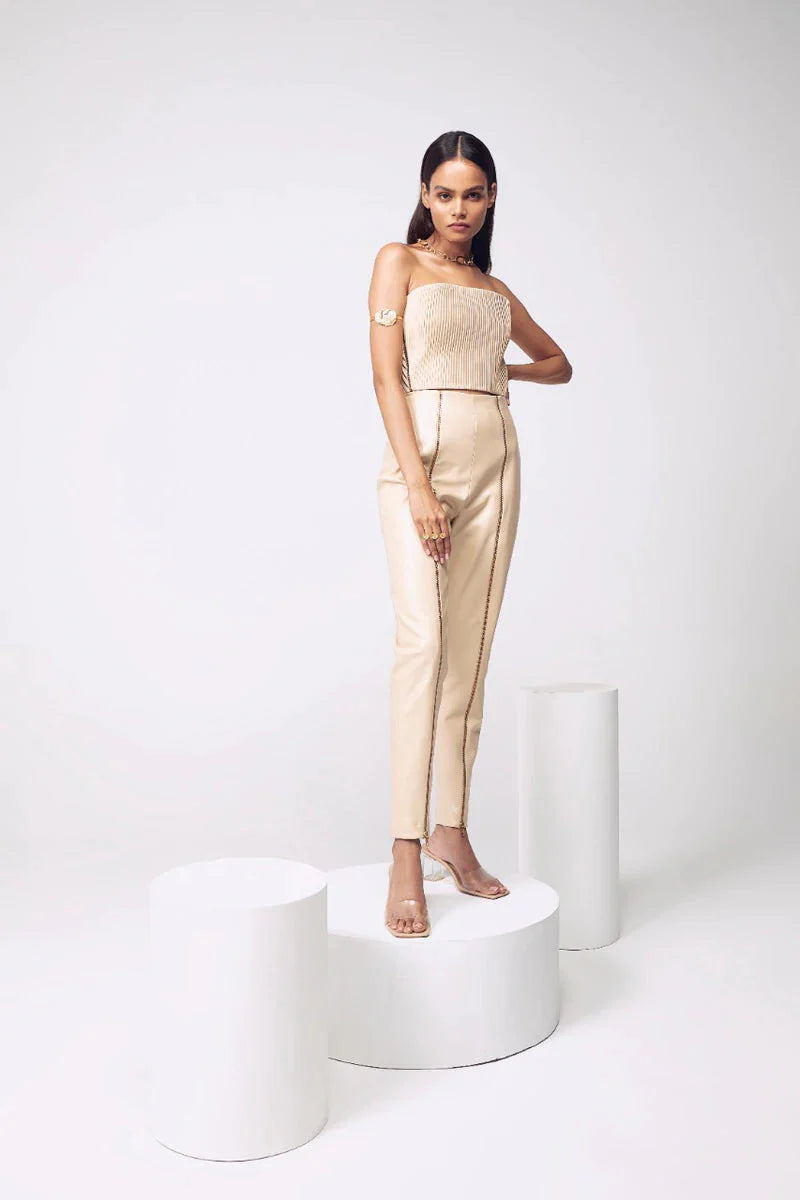 Versatile and minimal crop top collection from Mannat Gupta which every woman will love to have. You can style in this beautiful gold corseted crop top which is made using artificial leather. The beige bandeau crop top is hand-pleated all around which adds a beautiful texture. The top comes with gold metal zippers on both sides for a detachable element. Pair this crop top with leather shorts or trousers, minimal gold jewelry and high sandals for your next night out.