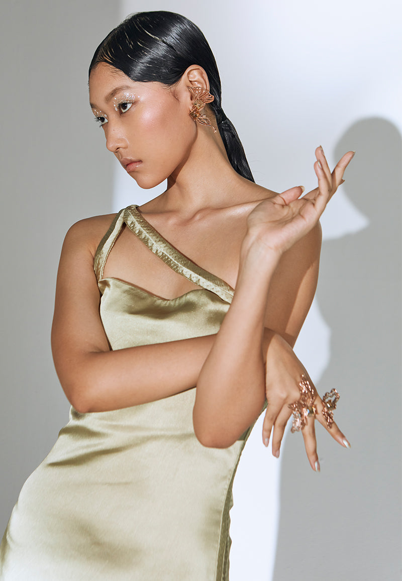 Understated yet impactful, this olive green luxurious satin dress features a unique pleating detail on both the side seams and the straps. It has a soft cowl neckline and falls mid-length with an impactuful side slit that comes to the front. It has a zip closure at the center back. Wear it for casual parties or Sunday brunches with minimal gold jewelry and short heeled sandals.