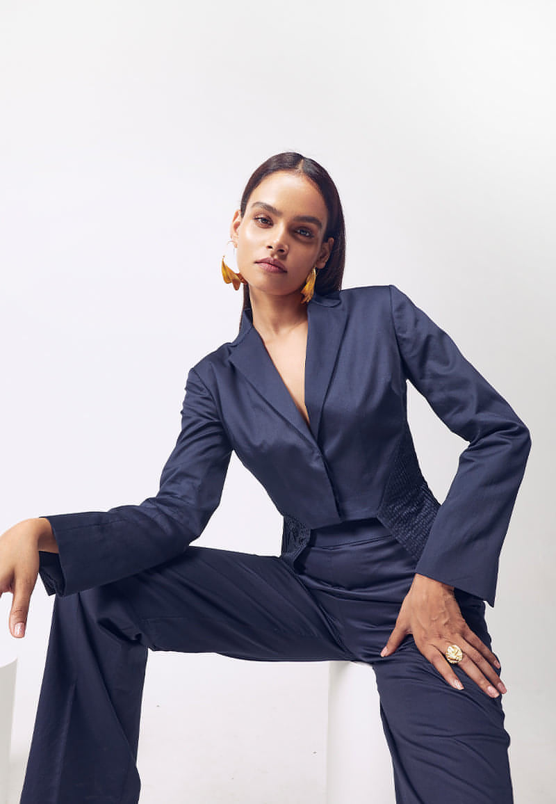 Mannat Gupta's premuim collection of women's co-ord sets. This jacket and pant co-ord set is made is soft cotton satin in navy blue. The collared cropped jacket with hidden buttons on the front features long sleeves and hand pleating details on both sides that accentuate a woman's body. The navy blue jacket comes with a high-waisted flared pant with inseam pockets for functionality in the same color. Pair yours with pumps and minimal, versatile gold jewelry for your next meeting or work.